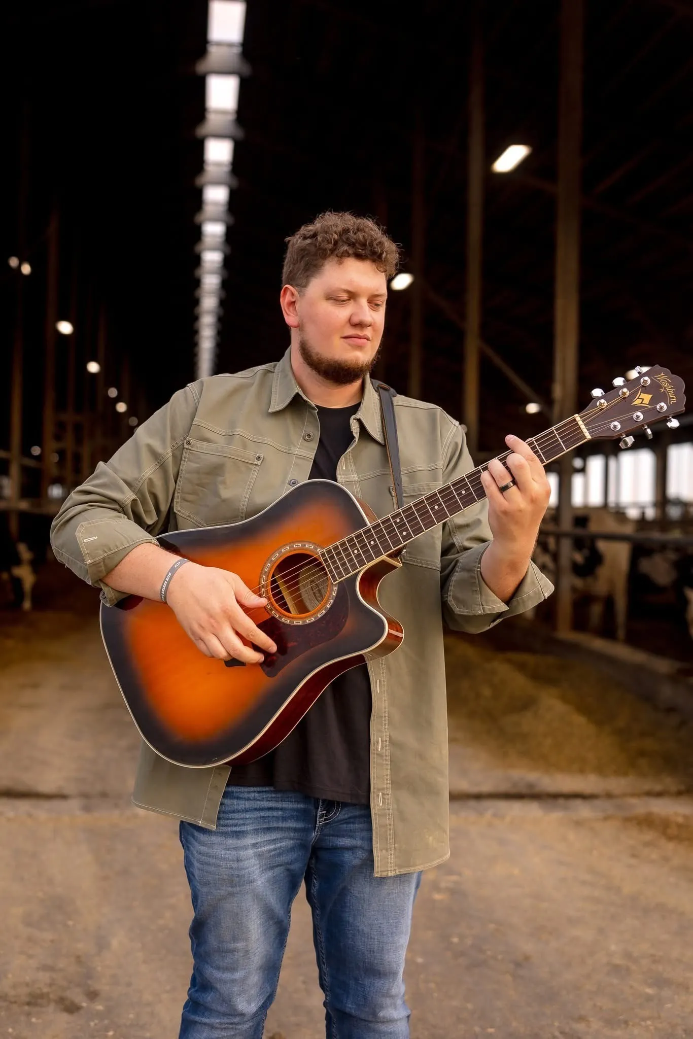Isaac Buschur playing guitar in a dairy barn